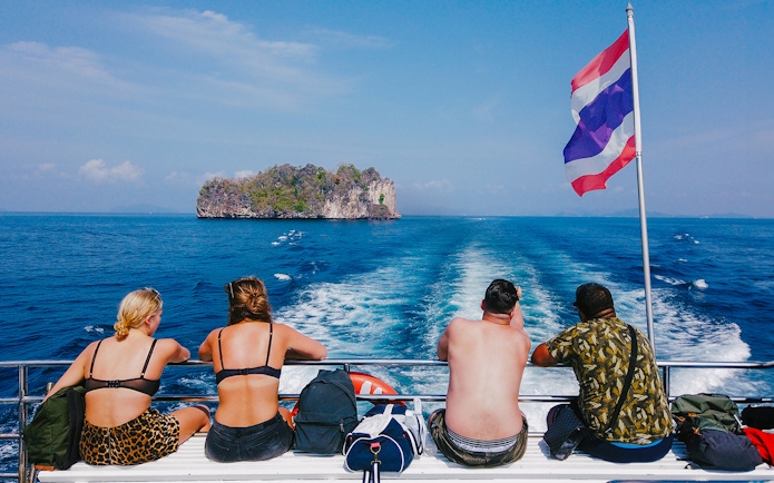 Tourists on a cruise ship in the Andaman Sea with an island in the distance.