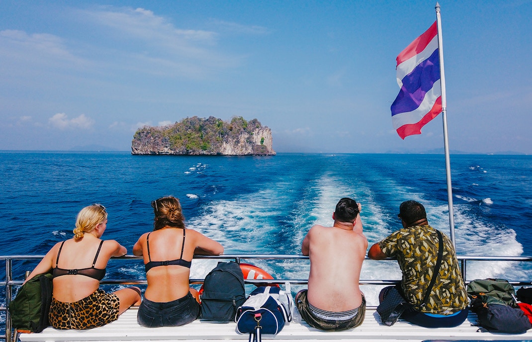 Tourists on a cruise ship in the Andaman Sea with an island in the distance.