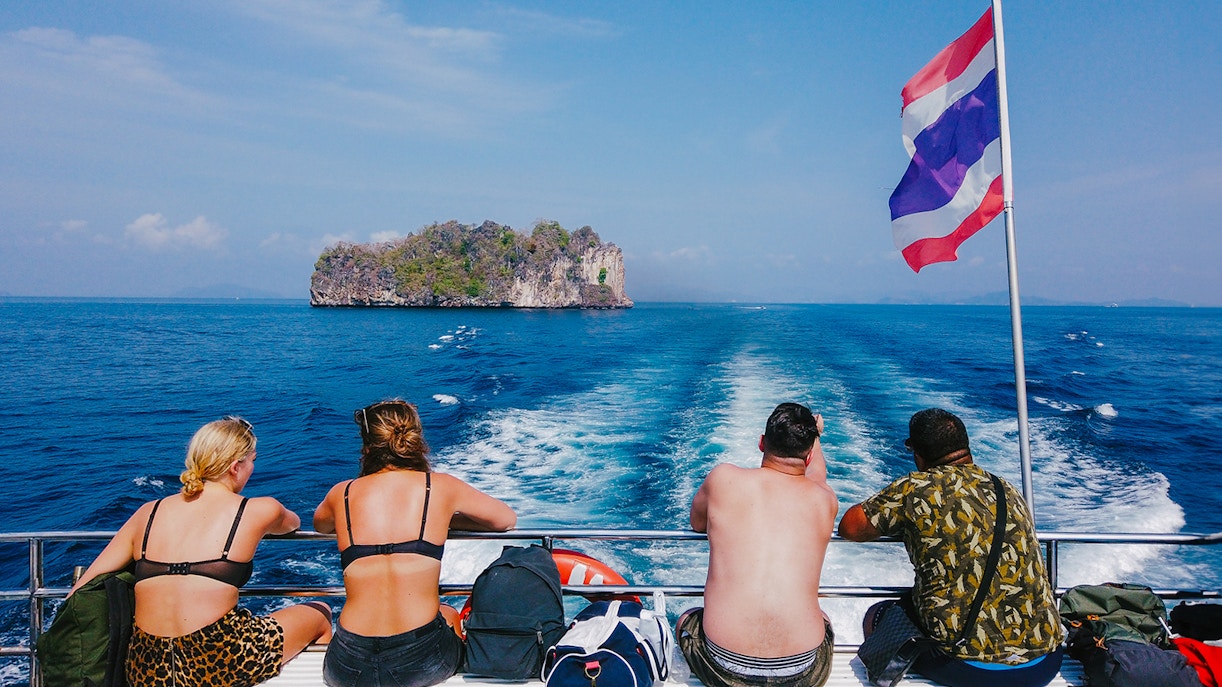 Tourists on a cruise ship in the Andaman Sea with an island in the distance.