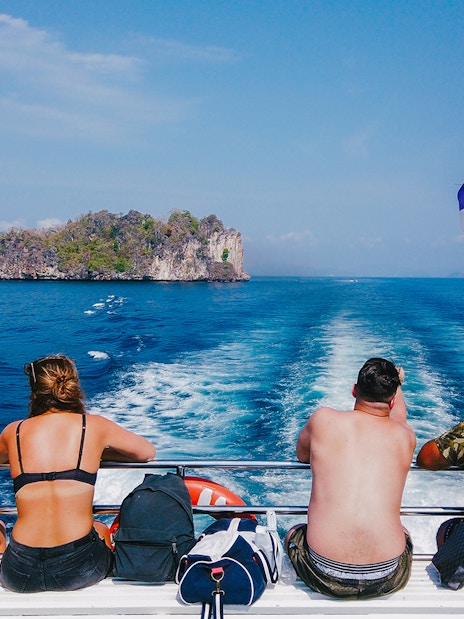 Tourists on a cruise ship in the Andaman Sea with an island in the distance.