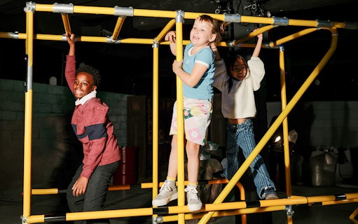 Children playing on a yellow jungle gym at iCandy Experience in NYC.