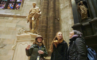 Visitors admiring a statue inside Milan Duomo.