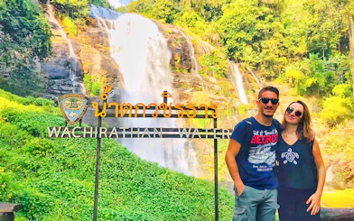 Couple in front of Wachirathan Waterfall sign on Doi Inthanon tour, Thailand.