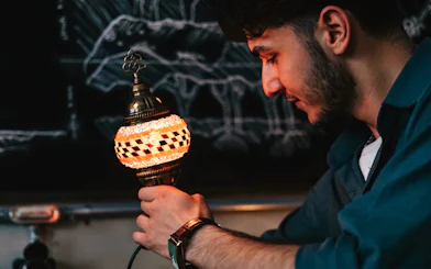 Guest holding a mosaic lamp at Istanbul Turkish Mosaic Lamp Workshop.