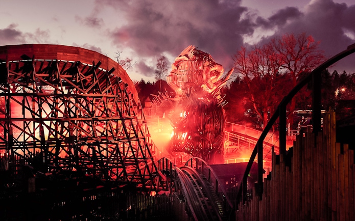 Wicker Man ride at Alton Towers with fiery wooden structure at dusk.