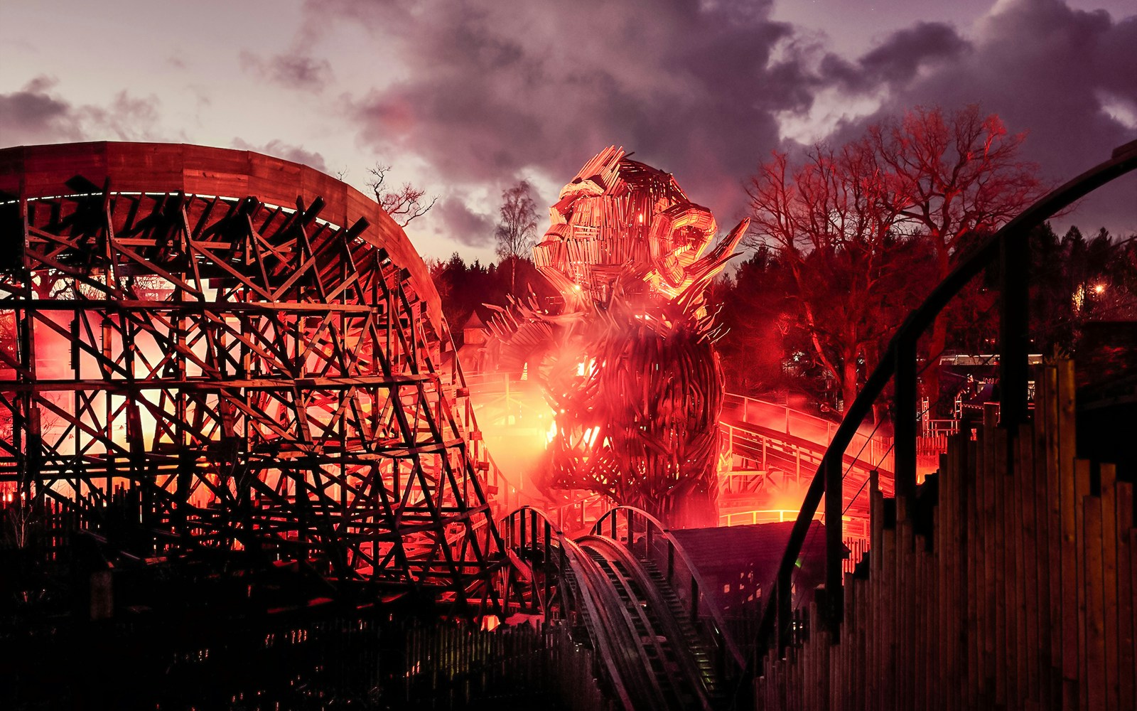 Wicker Man ride at Alton Towers with fiery wooden structure at dusk.