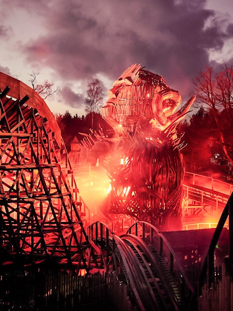 Wicker Man ride at Alton Towers with fiery wooden structure at dusk.