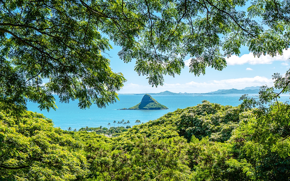 Chinaman's Hat island view from Kualoa Ranch, Hawaii, framed by lush greenery.