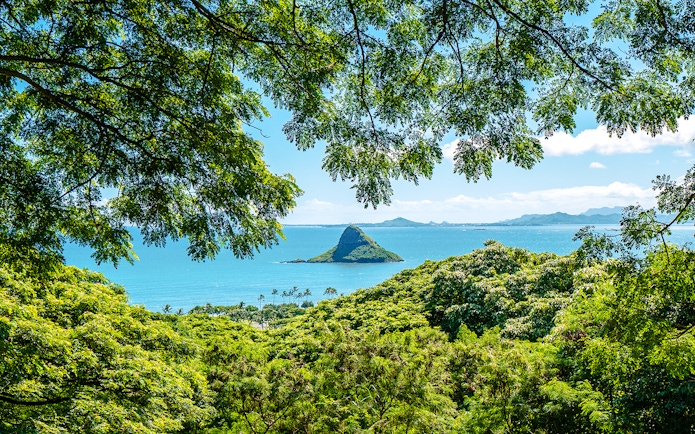 Chinaman's Hat island view from Kualoa Ranch, Hawaii, framed by lush greenery.