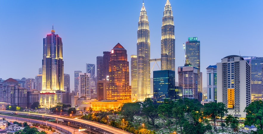 Petronas Twin Towers illuminated at night in Kuala Lumpur skyline.