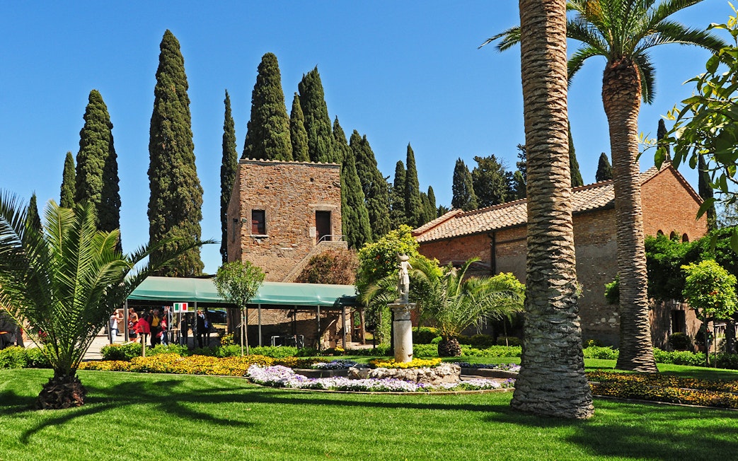 Underground catacombs entrance with garden and historic building in the background.