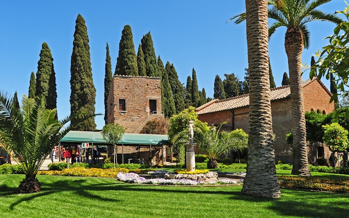 Underground catacombs entrance with garden and historic building in the background.
