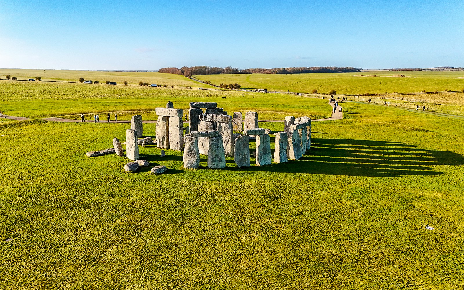Stonehenge stone circle on a sunny day with green fields, viewed from above.