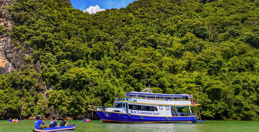 Tourists kayaking near a tour boat at Phang Nga Bay, Thailand.