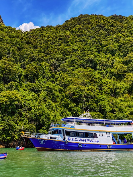 Tourists kayaking near a tour boat at Phang Nga Bay, Thailand.