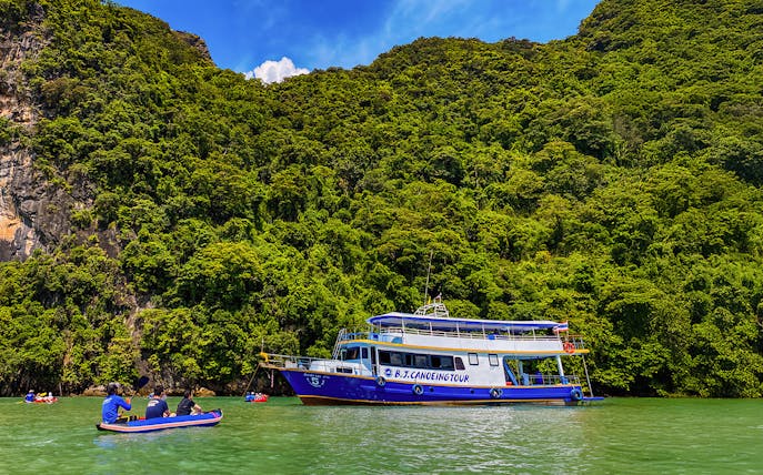 Tourists kayaking near a tour boat at Phang Nga Bay, Thailand.