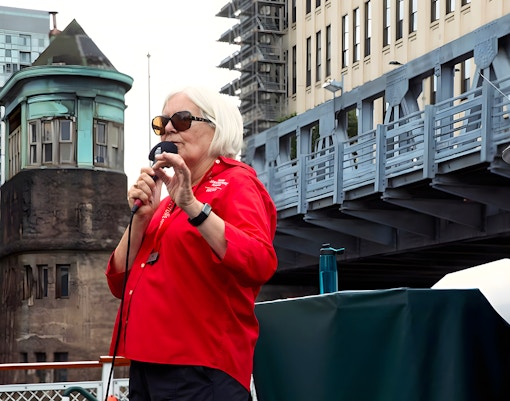 Guide speaking on the 'Chicago First Lady' cruise with city architecture in the background.