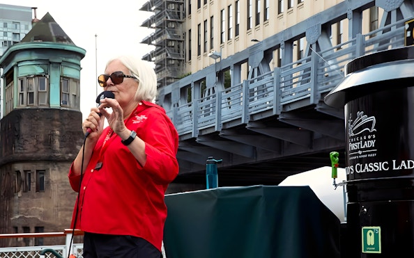 Guide speaking on the 'Chicago First Lady' cruise with city architecture in the background.