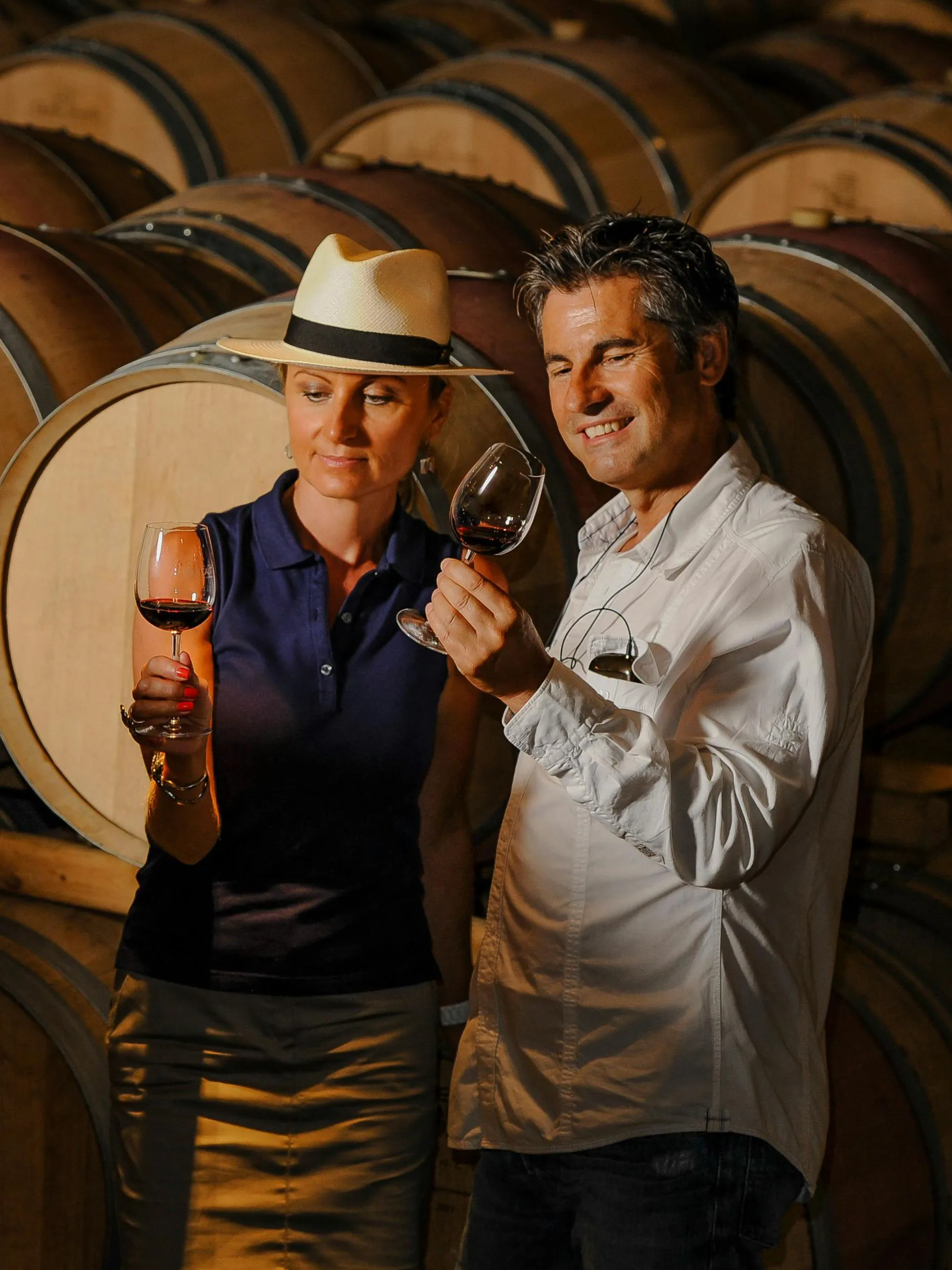 Couple tasting wine in a Porto cellar surrounded by barrels.