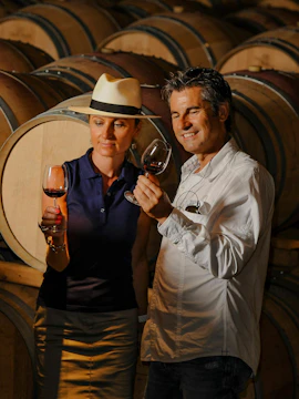 Couple tasting wine in a Porto cellar surrounded by barrels.