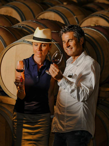 Couple tasting wine in a Porto cellar surrounded by barrels.