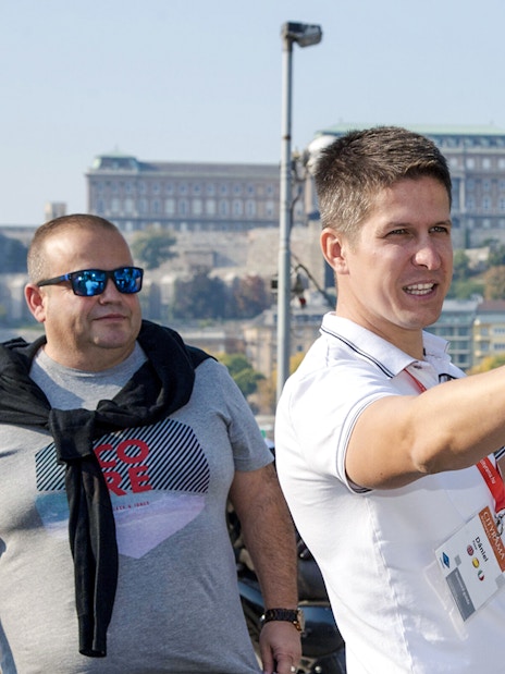 Tour guide directing guests during a Budapest walking tour with Buda Castle in the background.