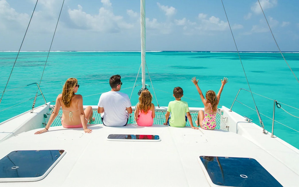 Family enjoying catamaran tour on turquoise waters near Isla Mujeres.