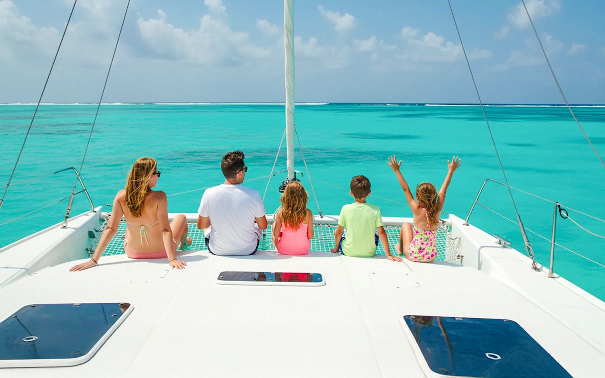 Family enjoying catamaran tour on turquoise waters near Isla Mujeres.