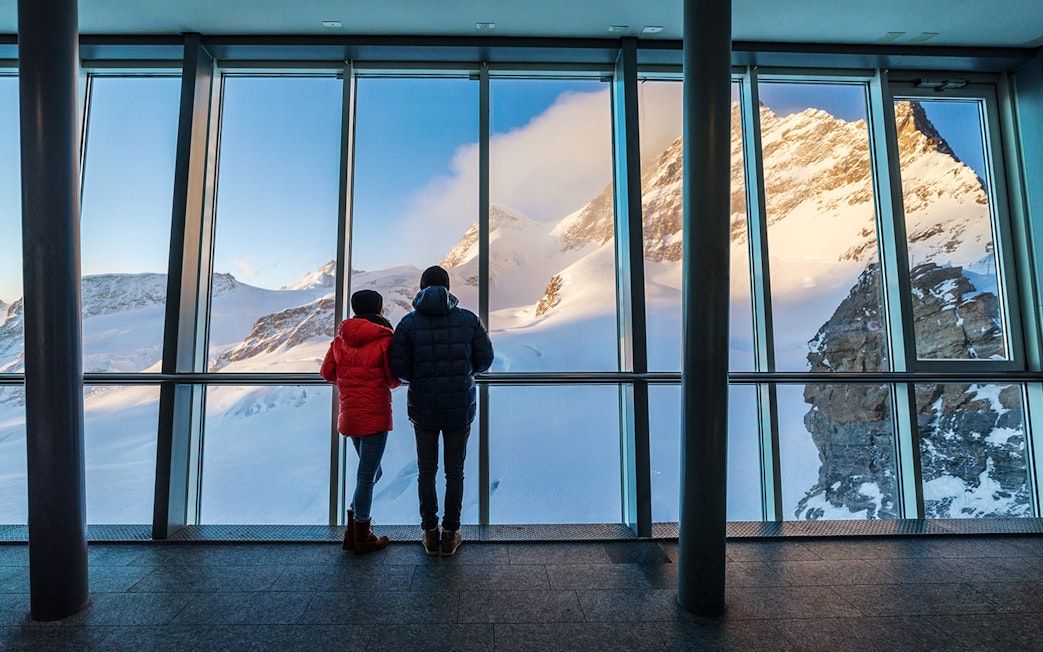 Visitors viewing snowy peaks from Jungfraujoch observatory, Switzerland.