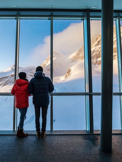 Visitors viewing snowy peaks from Jungfraujoch observatory, Switzerland.