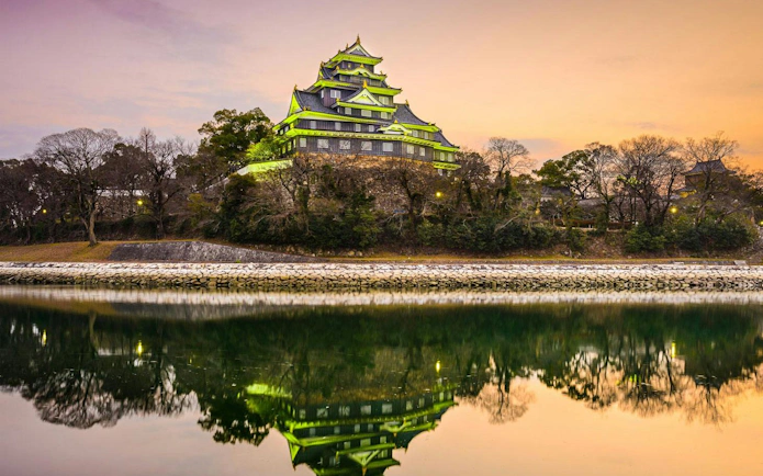 Okayama Castle reflecting in a river at sunset, Okayama, Japan.