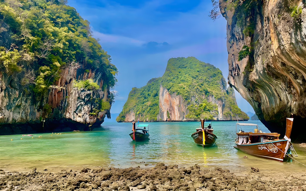 Speed boats anchored near limestone cliffs on Krabi Hong Island, Thailand.