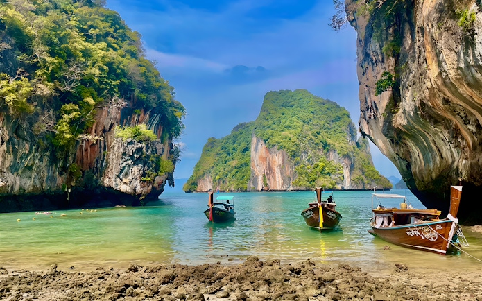 Speed boats anchored near limestone cliffs on Krabi Hong Island, Thailand.