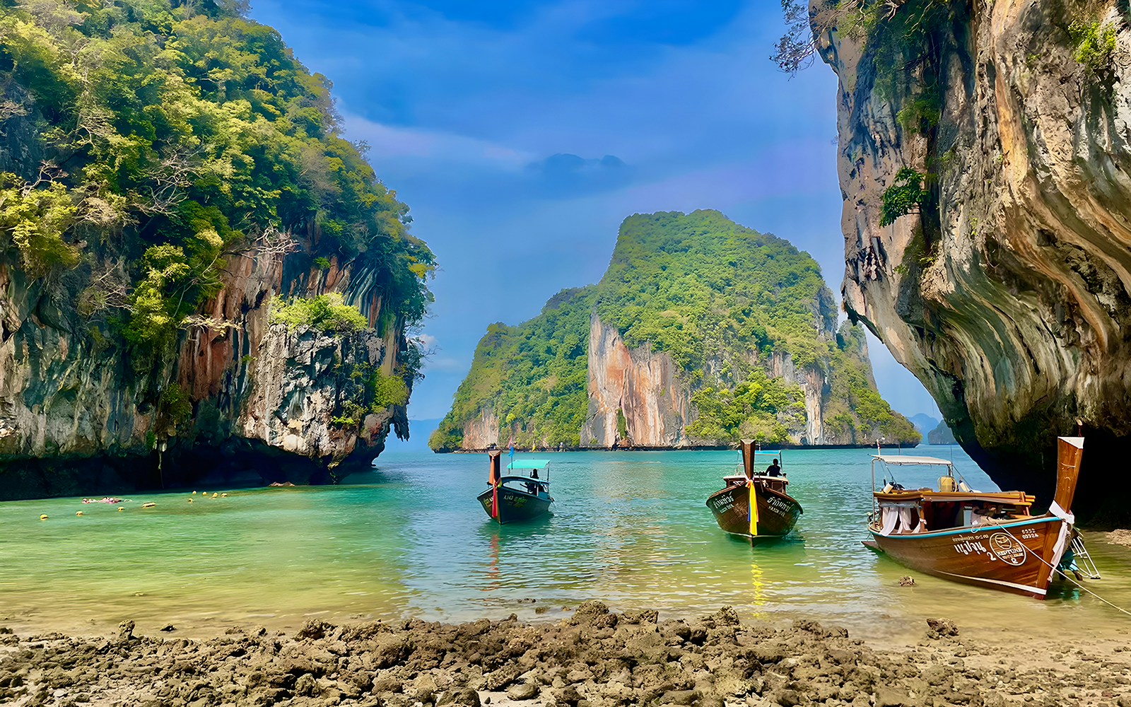Speed boats anchored near limestone cliffs on Krabi Hong Island, Thailand.