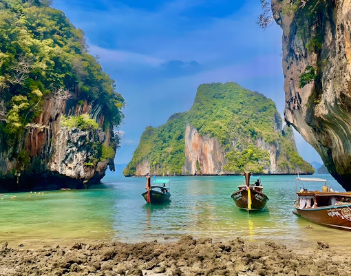 Speed boats anchored near limestone cliffs on Krabi Hong Island, Thailand.