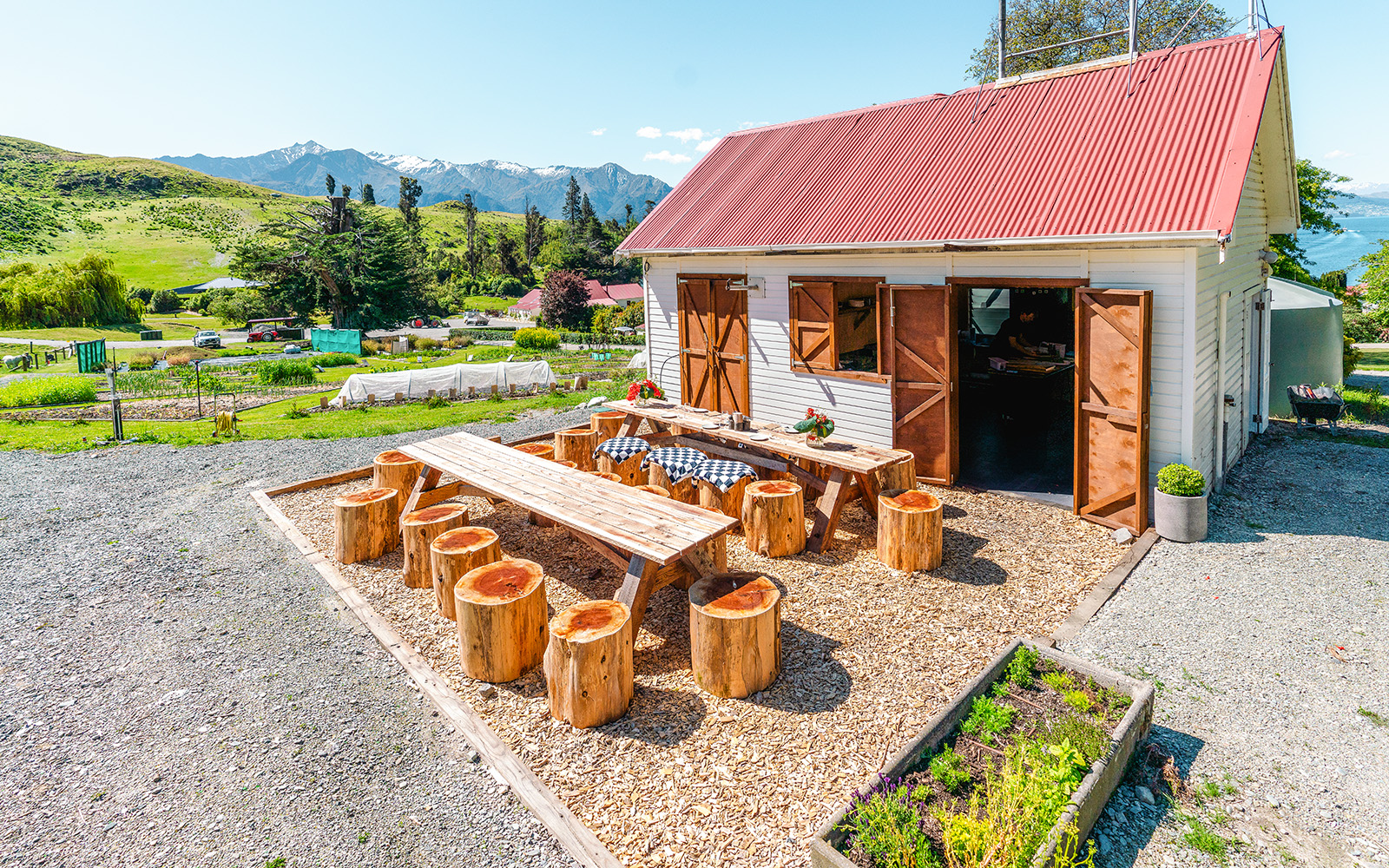 Outdoor dining area at Walter Peak Gourmet BBQ Experience with wooden tables and mountain view.