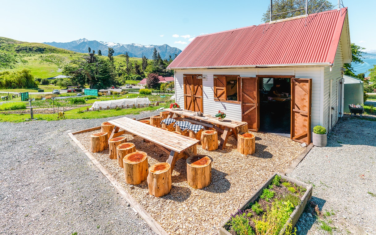 Outdoor dining area at Walter Peak Gourmet BBQ Experience with wooden tables and mountain view.