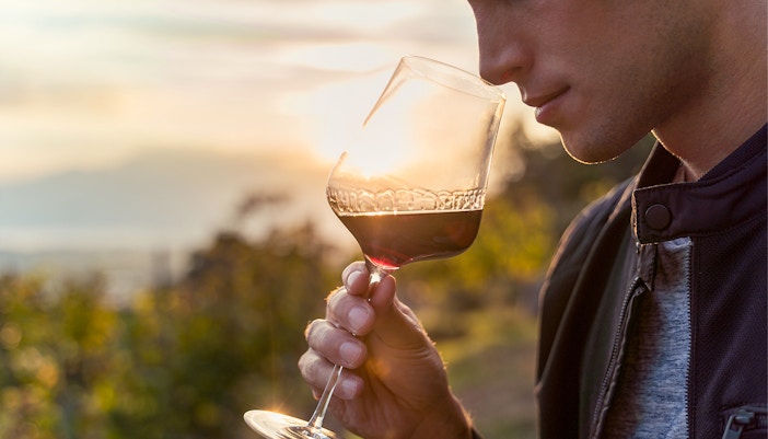 Man savoring wine outdoors at sunset.