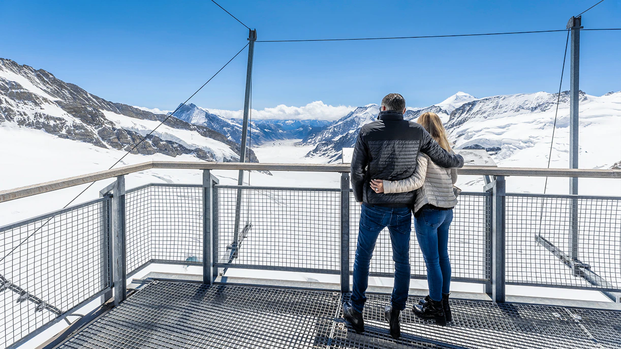 Visitors enjoying the view from Jungfraujoch Observatory, overlooking snowy mountains.
