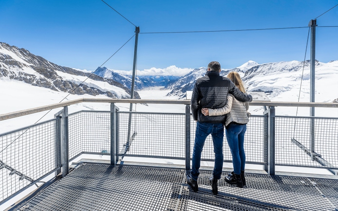 Visitors enjoying the view from Jungfraujoch Observatory, overlooking snowy mountains.