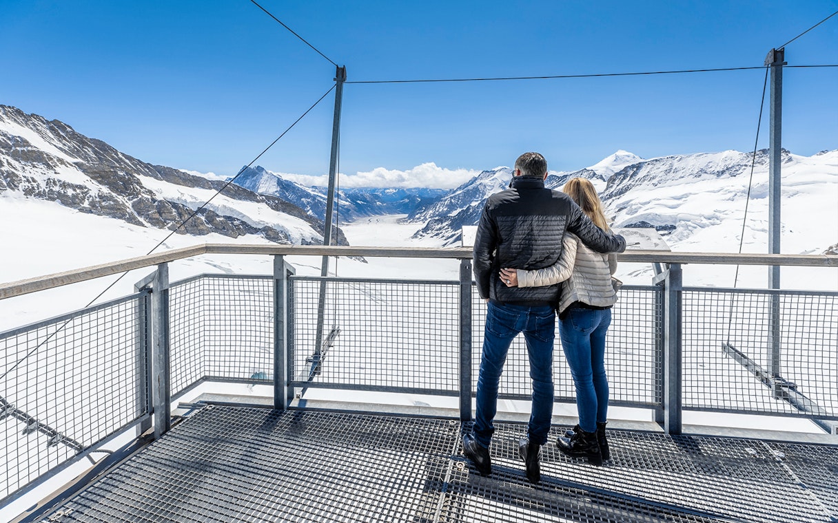 Visitors enjoying the view from Jungfraujoch Observatory, overlooking snowy mountains.