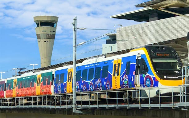 Train at Brisbane Airport station with control tower in background.