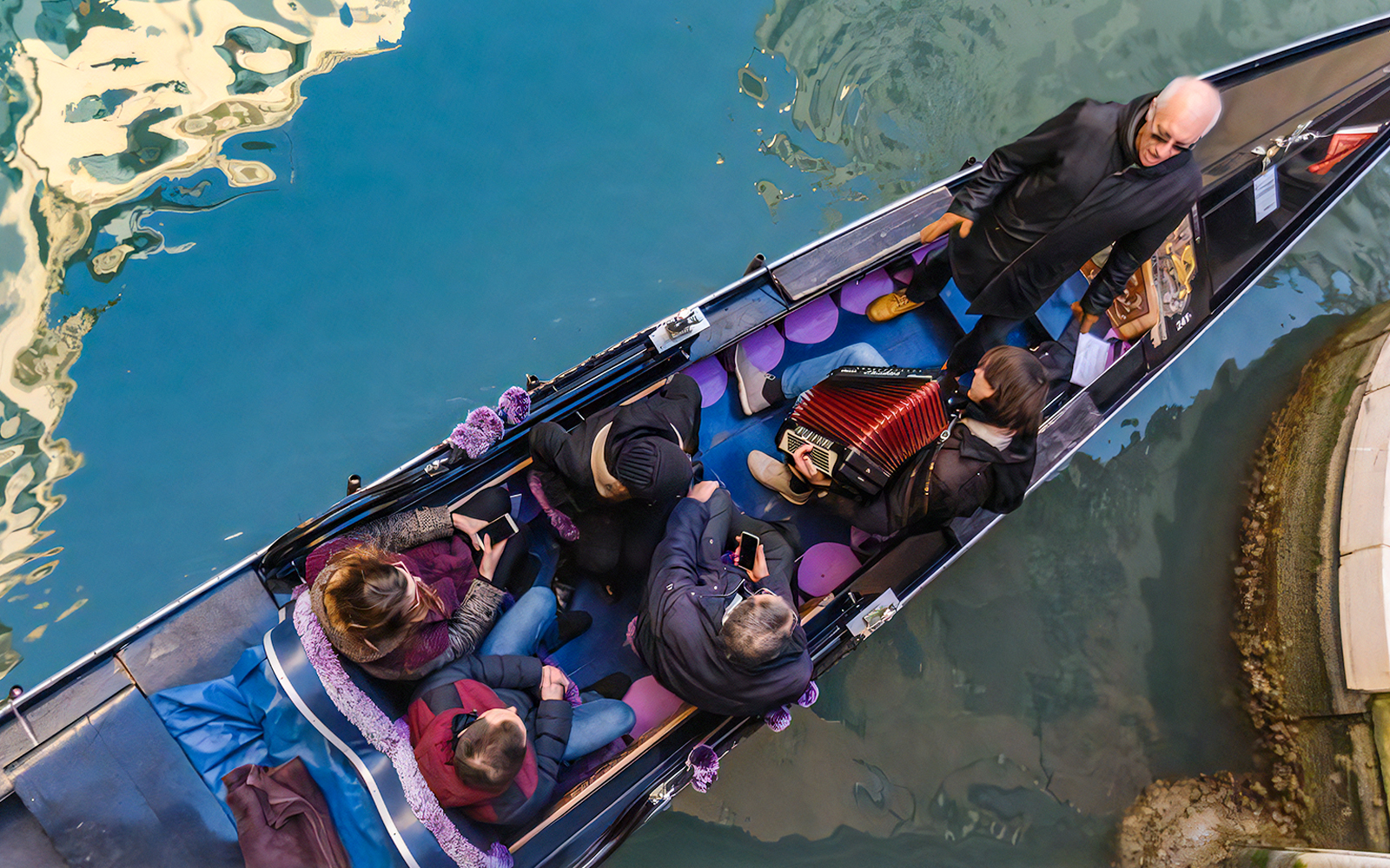 Gondola ride in Venice with musician playing accordion and passengers enjoying the serenade.