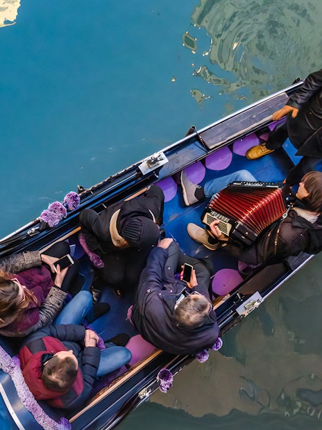 Gondola ride in Venice with musician playing accordion and passengers enjoying the serenade.
