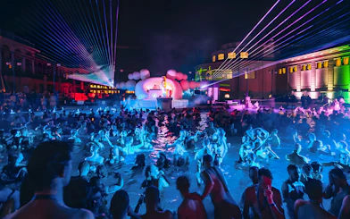 Crowd enjoying Sparty event with DJ and lights at Széchenyi Thermal Bath, Budapest.