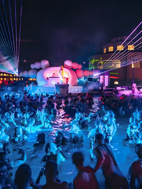 Crowd enjoying Sparty event with DJ and lights at Széchenyi Thermal Bath, Budapest.