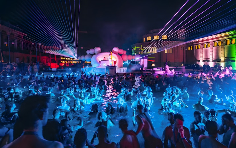 Crowd enjoying Sparty event with DJ and lights at Széchenyi Thermal Bath, Budapest.