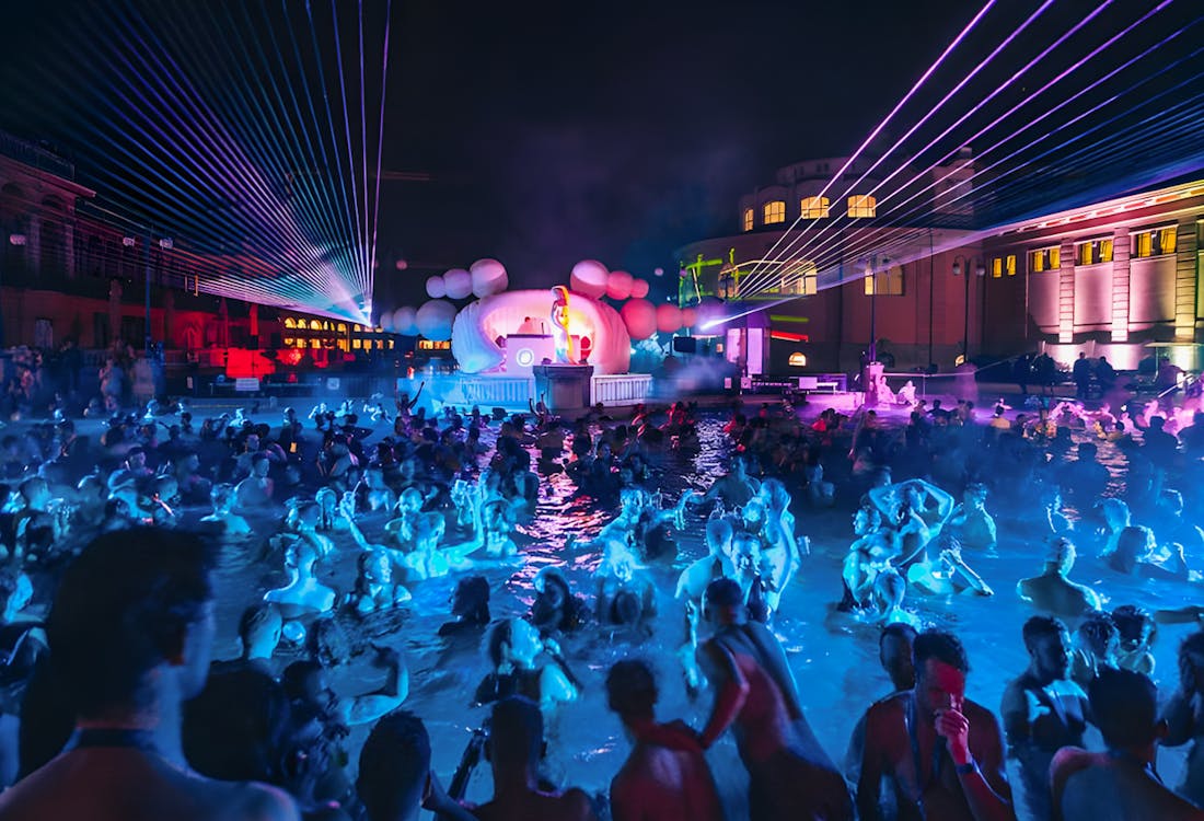 People enjoying Sparty event in Széchenyi Thermal Bath, Budapest at night.