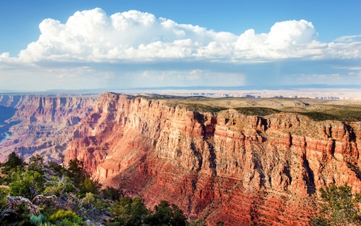 Grand Canyon view with layered red rock formations under a cloudy sky.