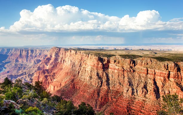 Grand Canyon view with layered red rock formations under a cloudy sky.